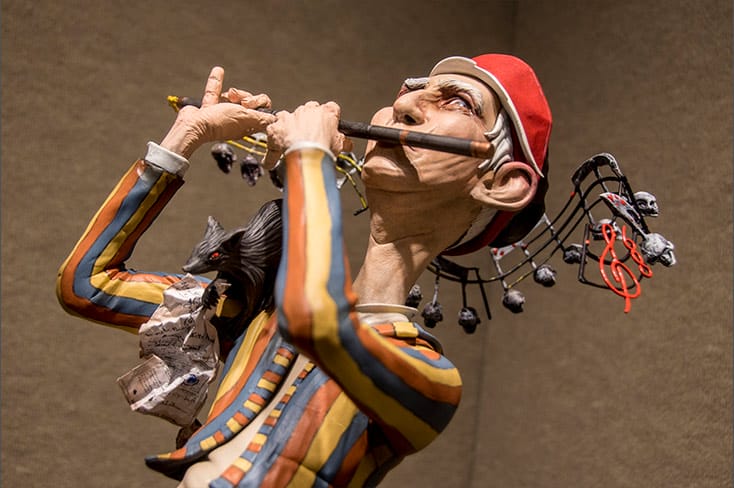 sculpture of man playing a flute
