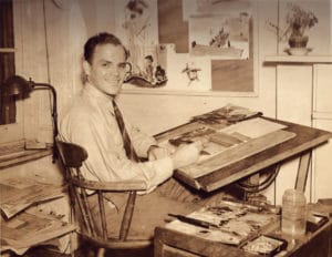 Hardie Gramatky sits at his studio desk painting in 1940