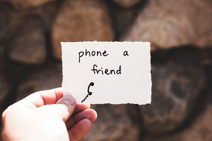 hand holding a card that reads phone a friend