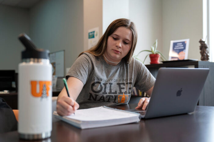 Student studying at table with computer